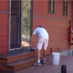 Worker painting deck in the backyard